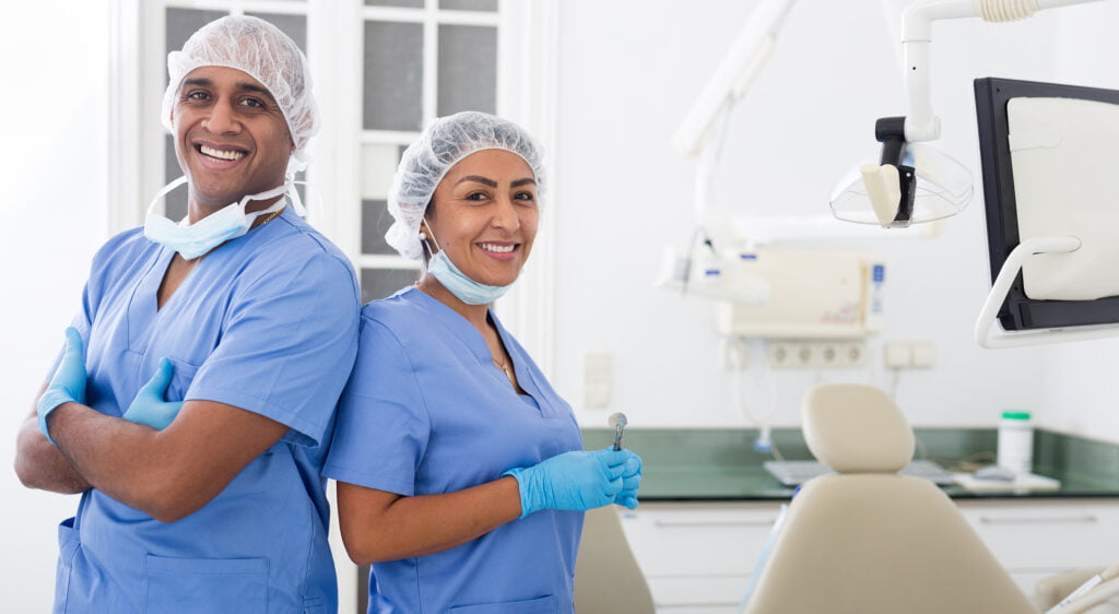 Dental Team Smiling in Clinic Two dental professionals in scrubs smiling confidently in a modern dental office