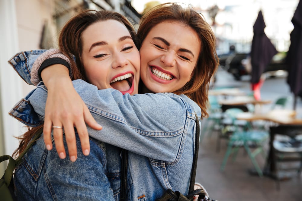 Two friends share laughter and bright smiles, showcasing the happiness of strong teeth and oral health. - Dentist in South Gate, CA