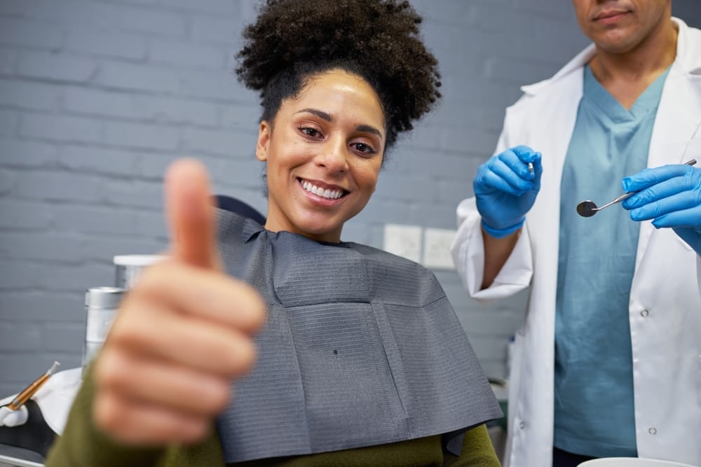 A smiling patient gives a thumbs up while sitting in a dental chair, showing relief and satisfaction after receiving immediate dental care – Emergency Dentist in San Fernando, CA.